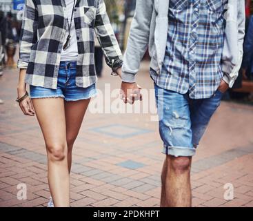 Passeggiata romantica. Immagine ritagliata di una coppia che passeggerà a mano lungo una strada asfaltata. Foto Stock