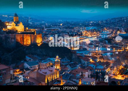 Tbilisi, Georgia. Cielo stellato notte cielo sopra skyline città, vista panoramica Vecchio quartiere storico di Kala. Paesaggio urbano notturno. Sera. Blu Foto Stock