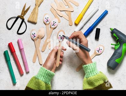 Passaggio 3. Dipingi il viso su un cucchiaio con un pittore acrilico nero. Rendere grazioso coniglietto decorazione da per Pasqua con i bambini. Vista dall'alto. Foto Stock