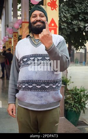 New Delhi, India - Dicembre 04 2022 - persone non identificate che mostrano le loro barrette con inchiostro dopo aver castato i voti di fronte al seggio di Delhi est Foto Stock