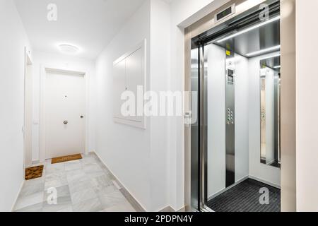 Ascensore esterno moderno e affidabile con vista sulla hall e le porte degli appartamenti in un nuovo edificio di appartamenti. Concetto di convenienza e high-tech Foto Stock