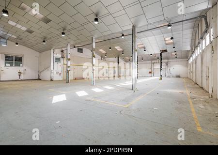 Garage con luci, pareti di colore chiaro, travi in metallo e soffitto preparato per la ristrutturazione in una sala per feste. Il concetto di locali spaziosi Foto Stock