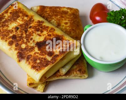 Frittelle ripiene ripiegate con salsa di panna sul piatto bianco primo piano Foto Stock