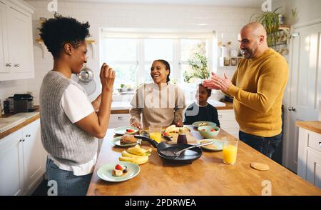 Ragazzo con sindrome di Down che ha frittelle a colazione con i genitori Foto Stock
