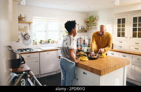 Ragazzo con sindrome di Down che fa frittelle a colazione con i genitori Foto Stock
