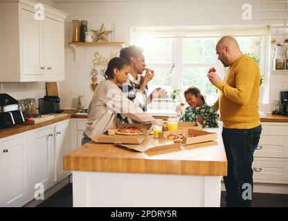 Famiglia con ragazzo con sindrome di Down che gusta la pizza da asporto per cena Foto Stock