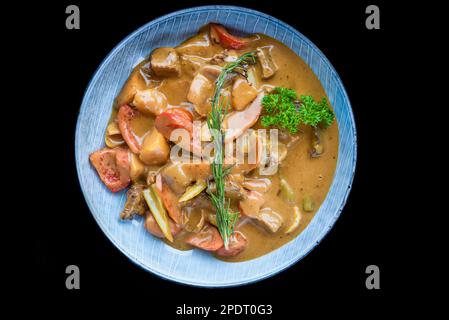 Stufato di manzo con verdure su piatto blu isolato su sfondo nero vista dall'alto Foto Stock