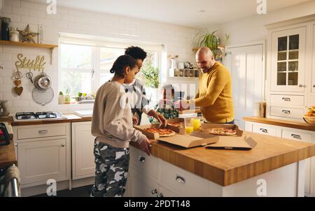 La famiglia gusterà la pizza da asporto per cena con un ragazzo con sindrome di Down Foto Stock