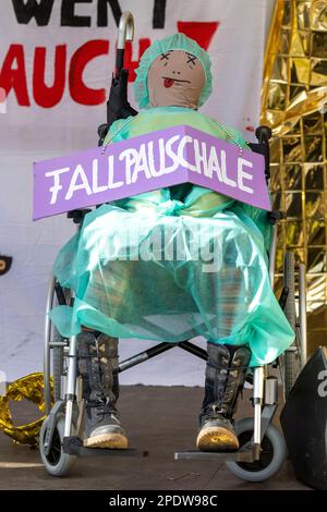 Gelsenkirchen, Germania. 15th Mar, 2023. Una bambola vestita da infermiera siede su una sedia a rotelle con il cartello "Fallpauschale". Verdi chiede scioperi in molte città del Nord Reno-Westfalia nel settore sanitario. Credit: Christoph Reichwein/dpa/Alamy Live News Foto Stock