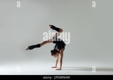 Simpatico piccolo gymnast fare il cavalletto su sfondo bianco Foto Stock