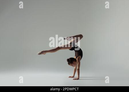 Simpatico piccolo gymnast fare il cavalletto su sfondo bianco Foto Stock