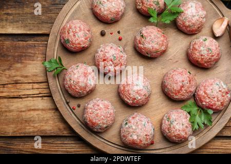 Molte polpette fresche crude e ingredienti su tavolo di legno, vista dall'alto Foto Stock