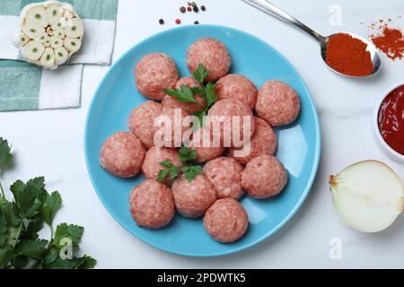 Molti polpette fresche crude e ingredienti su tavolo bianco, piatto Foto Stock