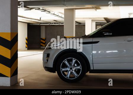 Auto bianca vicino alla colonna con strisce di avvertimento nel garage Foto Stock