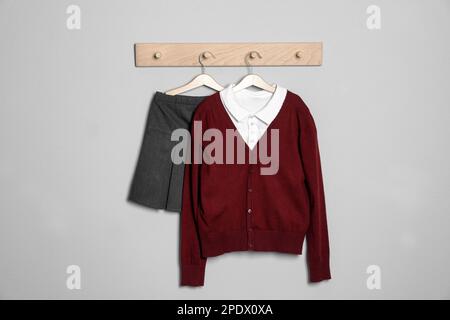 Camicia, jumper e gonna appesi a una parete leggera. Uniforme scolastica Foto Stock