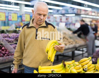 senor uomo pensionato che acquista banana in drogheria in supermercato Foto Stock