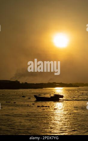 Campane di fumo da forni di mattoni come una barca di legno attraversa il fiume Mekong all'alba a Long Xuyen nel delta del Mekong in Vietnam. Foto Stock