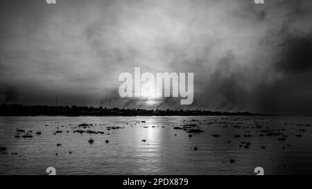 Il fumo campeggia dalle fornaci di mattoni come il sole sorge sopra il fiume Mekong con i suoi grumi di giacinto galleggiante di acqua a Long Xuyen nel delta del Mekong in Foto Stock