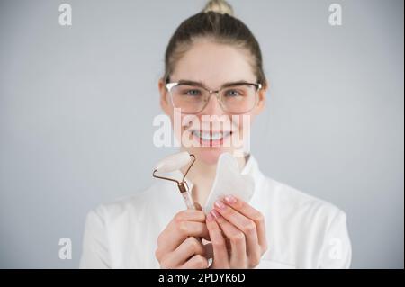 Medico estetista che tiene gouache raschietto e rullo. Foto Stock