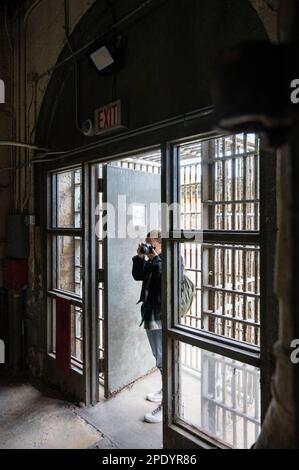 Giovane ragazza sorridente che visita e scatta foto nelle gallerie delle celle della prigione di Old Joliet Foto Stock