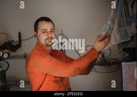 Meccanico auto maschio lavando le mani dopo la riparazione dell'automobile. L'operaio si lava le mani Foto Stock