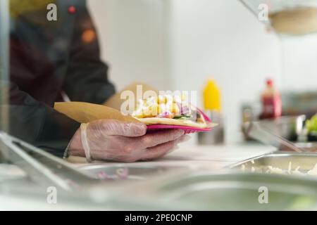 Chef che cucina greco pita souvlaki piatto con carne di pollo arrosto, verdure fresche e patatine fritte ricoperte di salsa bianca tzatziki su pita pane. Attenzione Foto Stock