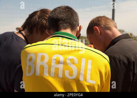 Khabarovsk, Russia - 21 Maggio 2017: Brasil testo sul retro del giallo sport shirt - giovani atleti parlando vista posteriore. 3 giocatori discutendo game strateg Foto Stock