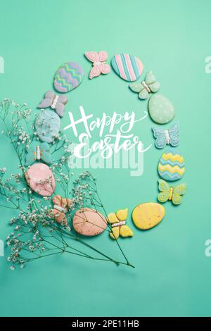 Banner pasquale su sfondo menta. Biscotti fatti in casa con pan di zenzero. Uova di Pasqua e biscotti a forma di coniglio e farfalla. Concetto di Pasqua. Foto Stock