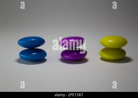 Primo piano di tre caramelle colorate su sfondo bianco Foto Stock