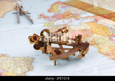 sestante nautico con ottica, bussola e righello giacente su carta mappa del mondo Foto Stock