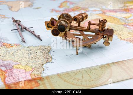 sestante nautico con ottica, bussola e righello giacente su carta mappa del mondo Foto Stock