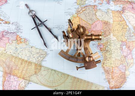 sestante nautico con ottica, bussola e righello giacente su carta mappa del mondo Foto Stock