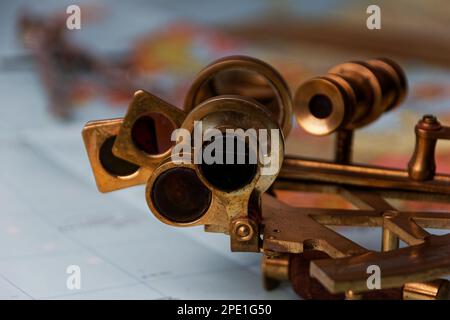 sestante nautico con ottica, bussola e righello giacente su carta mappa del mondo Foto Stock
