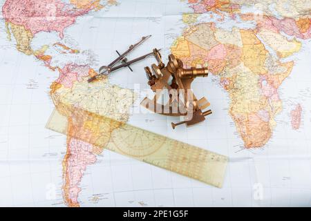 sestante nautico con ottica, bussola e righello giacente su carta mappa del mondo Foto Stock