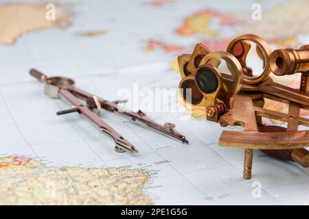 sestante nautico con ottica, bussola e righello giacente su carta mappa del mondo Foto Stock