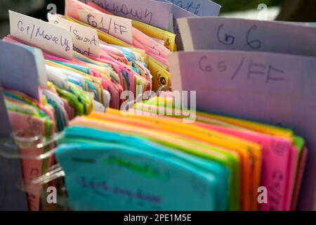 Una scheda di indice colorata organizzata in righe e memorizzata in scatole. Note scritte a mano su carta quadre e classificate Foto Stock