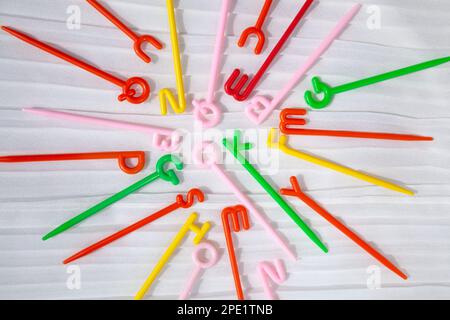 Bastoncini colorati in plastica con lettere inglesi in alto sparse sul bianco. Parola ok al centro. Divertente giocattolo educativo per bambini che imparano l'alfabeto Foto Stock