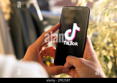 Tiktok sullo schermo del telefono cellulare. Giovane donna che tiene in mano uno smartphone con l'app Tik Tok. ROSARIO, ARGENTINA - 15 MARZO 2023. Foto Stock