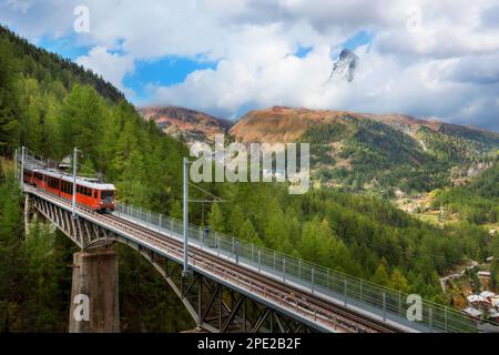 Zermatt, Svizzera. Treno turistico rosso Gornergrat sul ponte e panorama del Cervino sulle Alpi svizzere Foto Stock