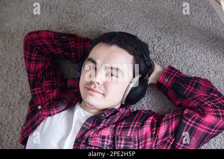 Ritratto di giovane uomo con cuffie, sorridente felicemente Foto Stock