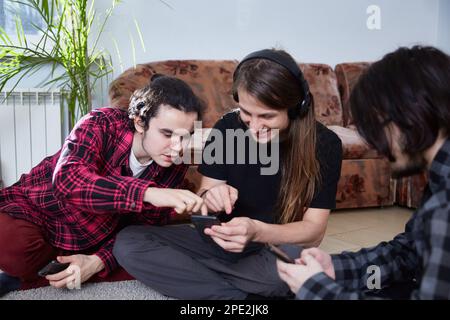 I giovani con smartphone nelle loro mani discutono di qualcosa insieme. Giovani dipendenza dalle nuove tendenze tecnologiche - momento di alienazione fo Foto Stock