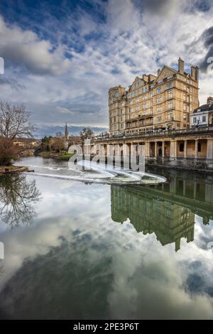 L'Empire Hotel e Weir sul fiume Avon con la chiesa di San Giovanni sullo sfondo, Bath, Somerset Foto Stock