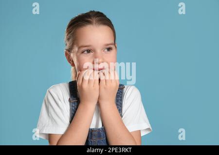 Carina bambina mordente le unghie su sfondo turchese. Spazio per il testo Foto Stock