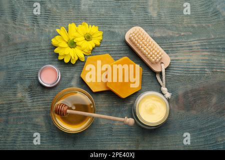 Composizione di posa piatta con cera d'api e prodotti cosmetici su tavola di legno blu Foto Stock