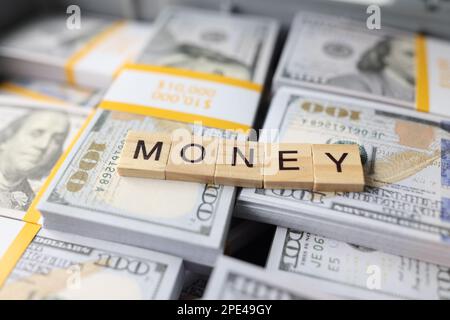 Denaro di parola raccolto da bar di legno su pile di dollari primo piano. Foto Stock