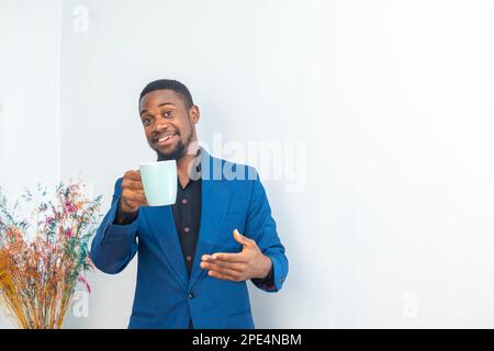Ritratto di umore felice giovane imprenditore africano che lavora tenendo una tazza da caffè indossare un abito da lavoro Foto Stock