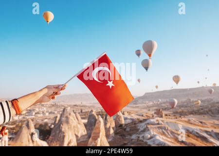 Con la bandiera turca in un punto panoramico si ammira il grandioso paesaggio di molti aerostati in alto sopra la Valle della Cappadocia in Turchia Foto Stock