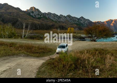 In autunno, un'auto del marchio Honda hr-v guida lungo una strada di montagna verso un ostacolo a forma di collina nelle montagne Altai. Foto Stock