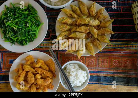 Vista dall'alto degli appetitosi involtini primaverili serviti sul piatto vicino alle alghe e ai gamberi fritti sul tavolo con tovagliolo e riso con bastoncini nel ristorante Vietnam Foto Stock
