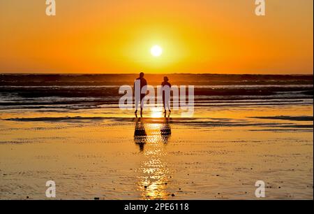 Due persone si godono il tramonto a Strand, Capo Occidentale, Sud Africa Foto Stock